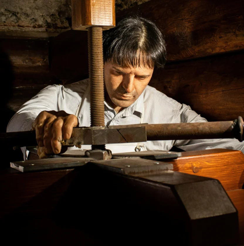 Handwerker an einer hölzernen Spindelpresse
