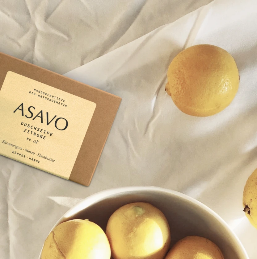 ASAVO Duschseife Zitrone verpackt neben frischen Zitronen